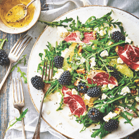 plate with arugula salad and blackberries