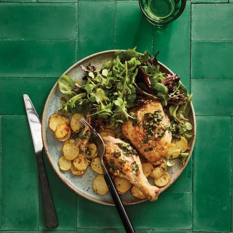 A plate of chicken and sides on a bright green table.