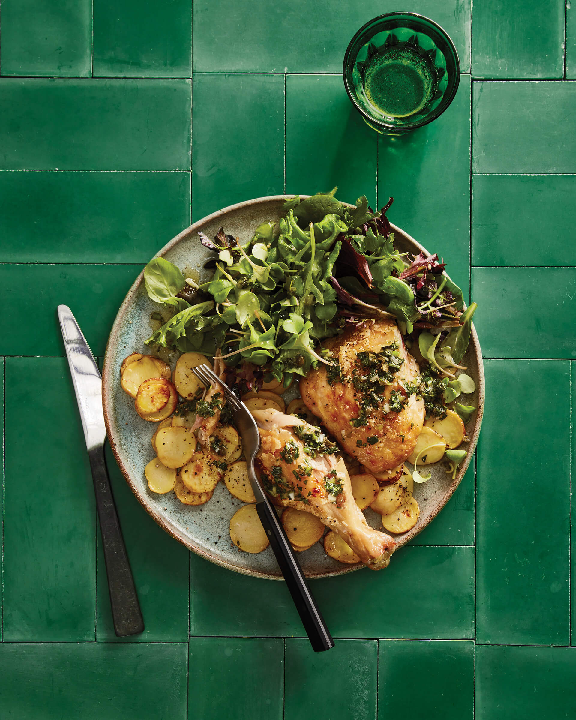 A plate of chicken and sides on a bright green table.
