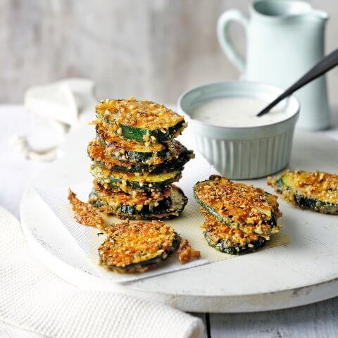 Stacks of crispy courgette with white aioli dip on the side.