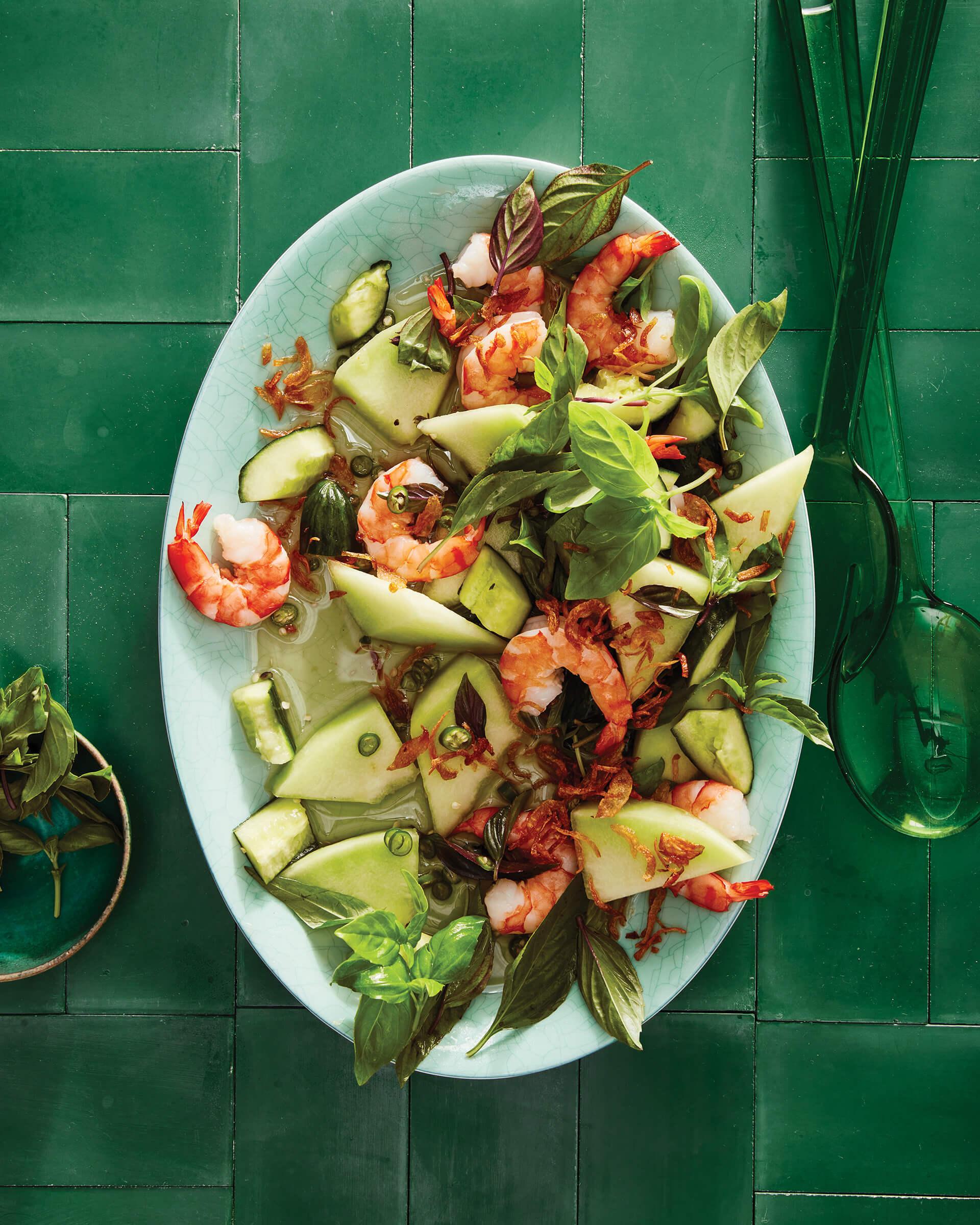 A platter of salad on a green tiled surface.