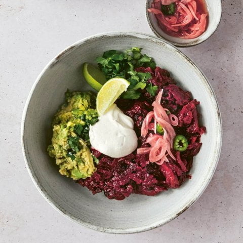 A bowl of chili with sauce and toppings on the side