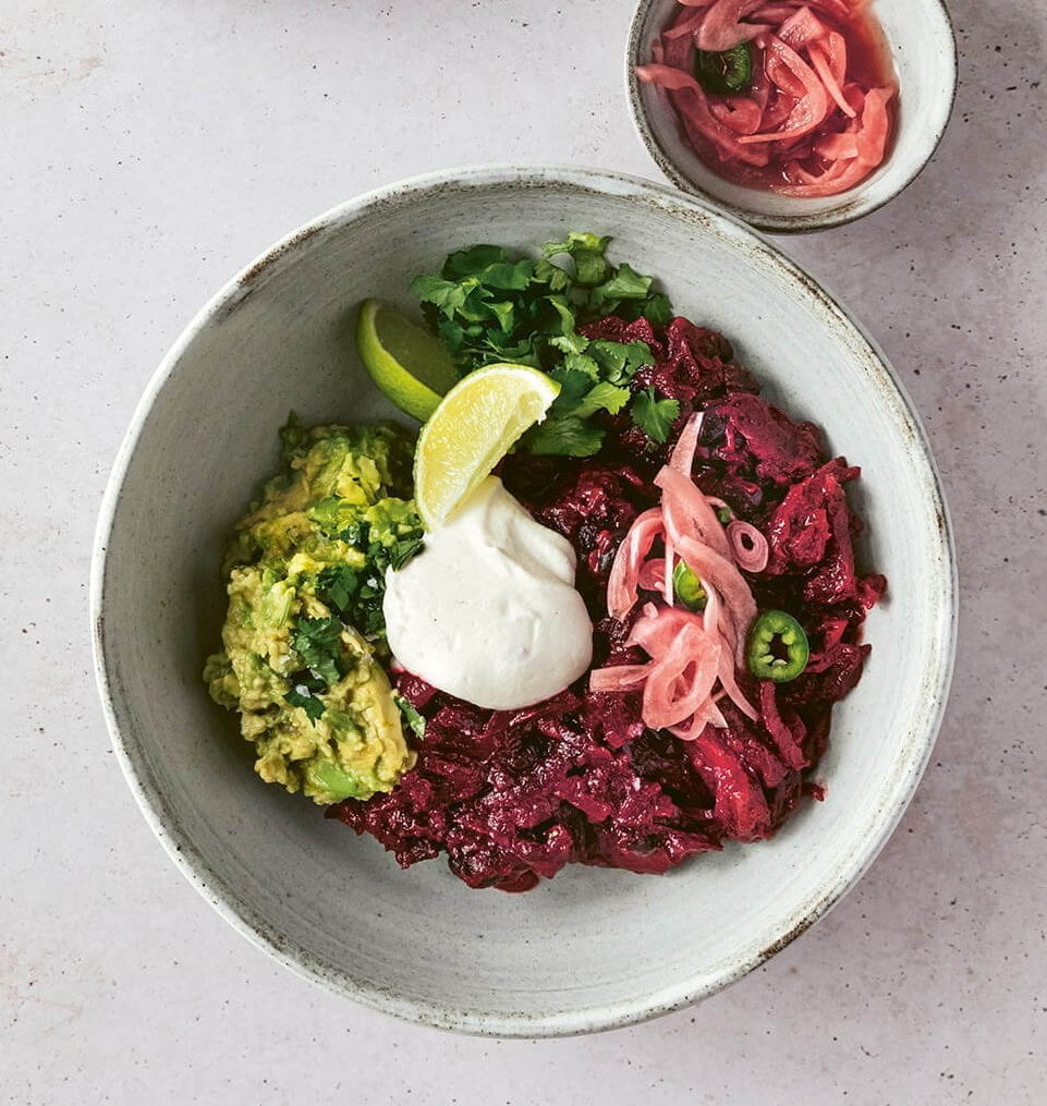 A bowl of chili with sauce and toppings on the side