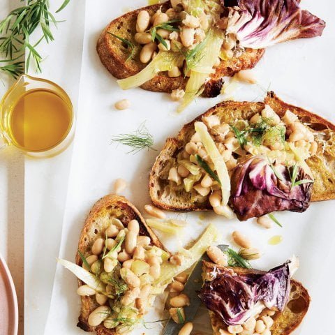 Slices of toast on a cutting board with beans and garnish
