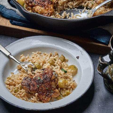 A black castiron pan with rice and chicken, a dish and a mug