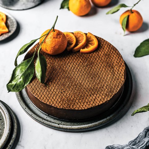 A chocolate cheesecake with whole and sliced orange garnish