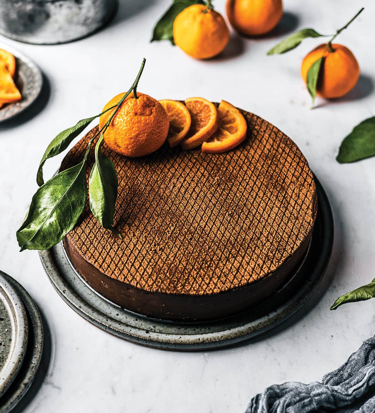 A chocolate cheesecake with whole and sliced orange garnish