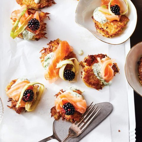 A white platter with bite-sized lox and latkes and cutlery
