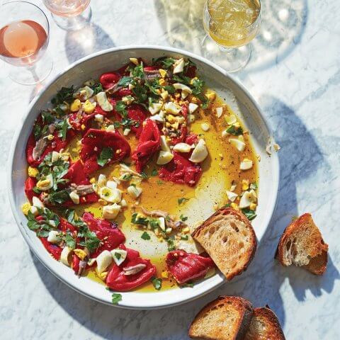 A white plate with salad and glasses of wine surrounding it