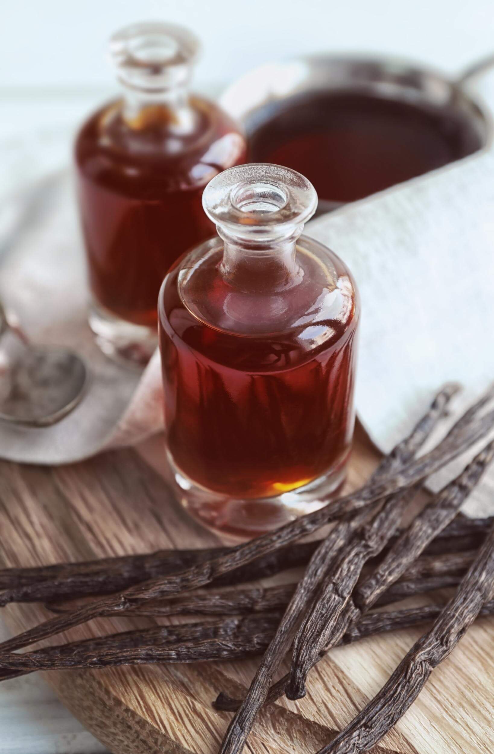 Glass bottles of vanilla extract with vanilla pods next to them