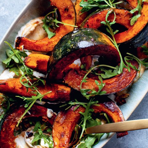 A closeup of squash wedges with arugula and yogurt