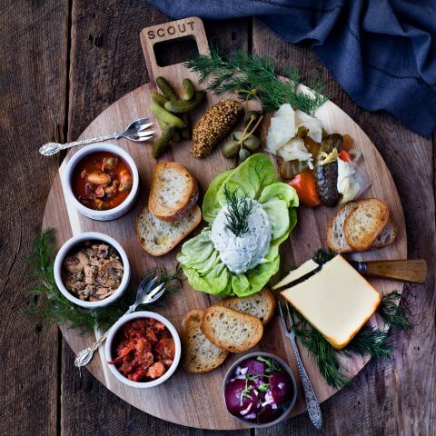 A board with three bowls of seafood, cheese and vegetables shot from above