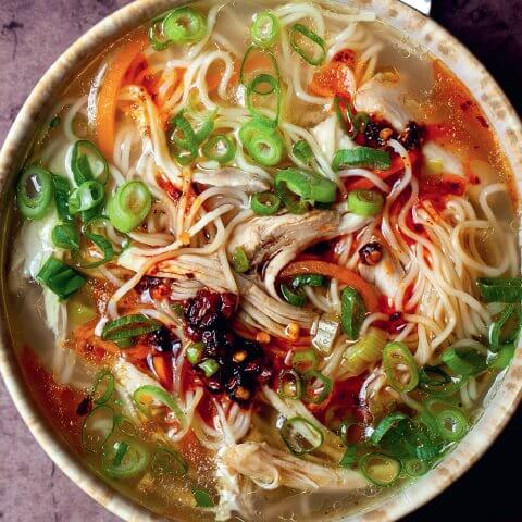 A bowl of ginger garlic chicken noodle soup from above