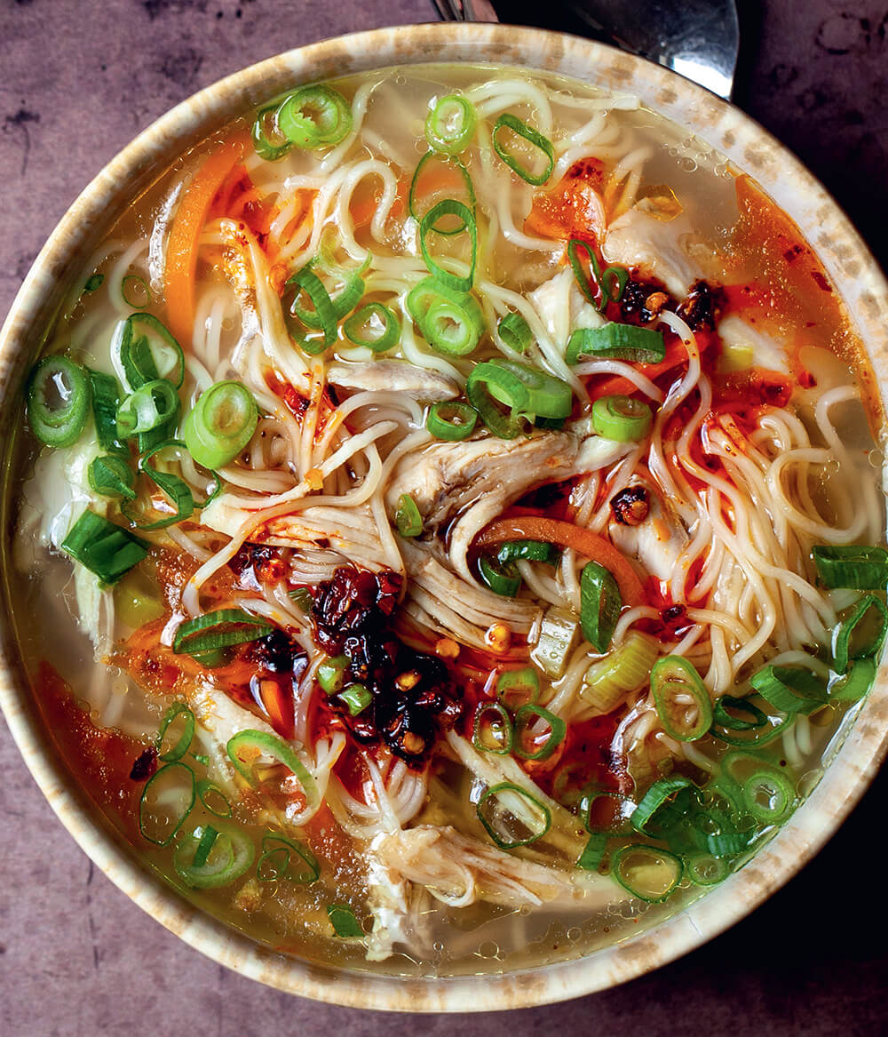 A bowl of ginger garlic chicken noodle soup from above