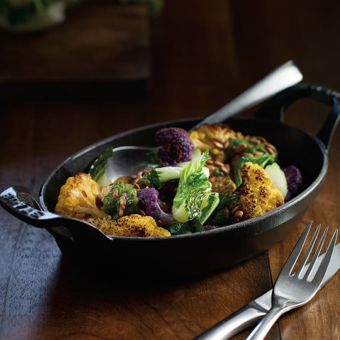 A black gratin dish with roasted vegetables