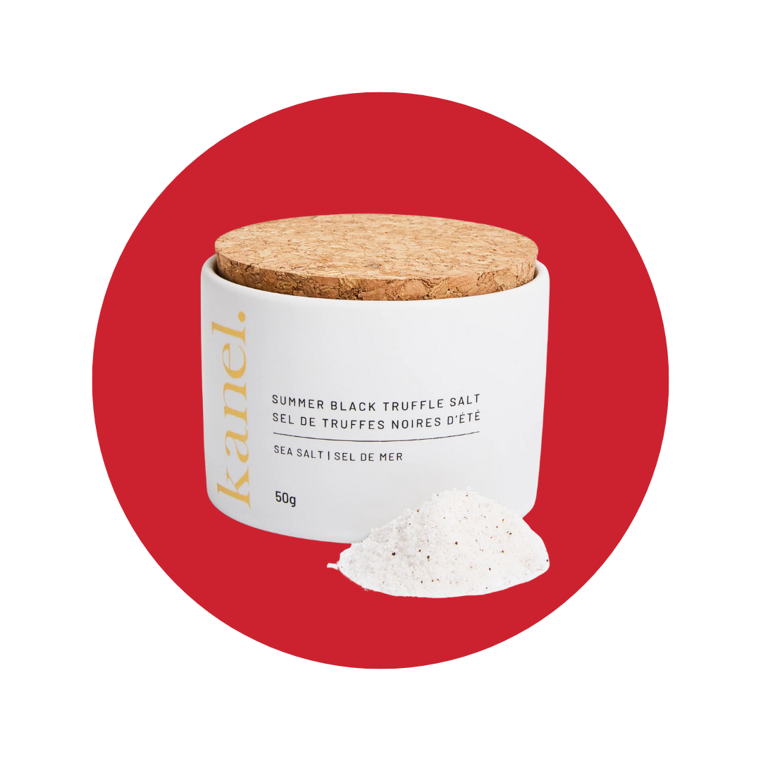 A white jar with a cork lid and a pile of truffle salt in front of a decorative red circle. 