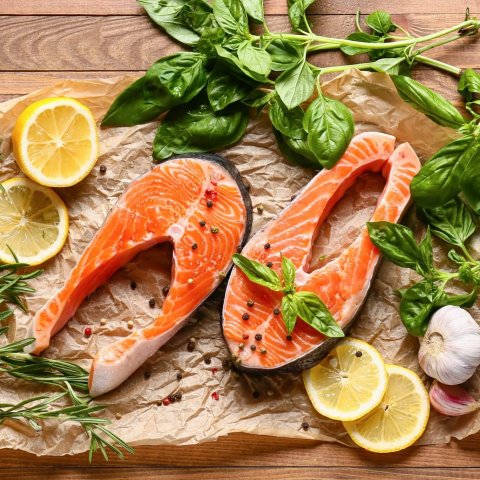 raw salmon, slices of lemon and fresh basil on cutting board