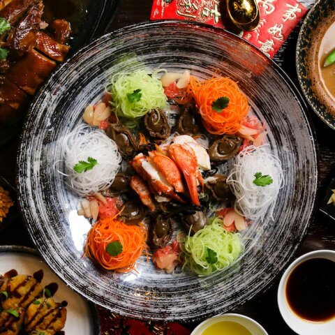 A yusheng salad from above with other dishes surrounding it.