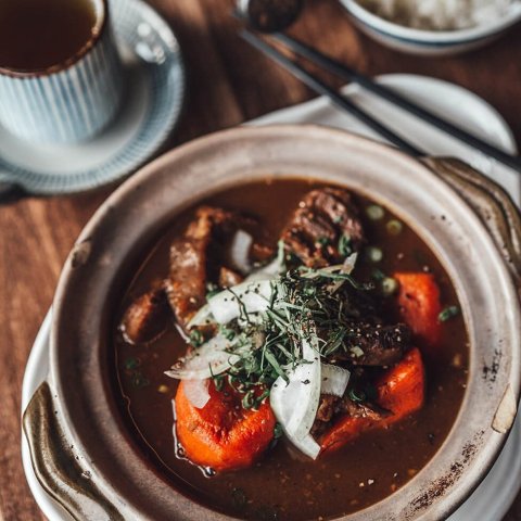 A bowl of beef stew, rice and tea.