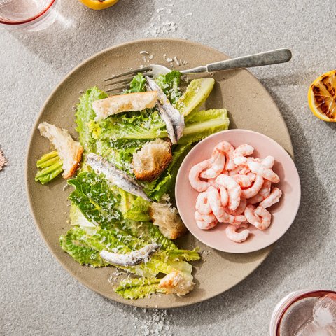 A caesar salad with shrimp on a tabletop.