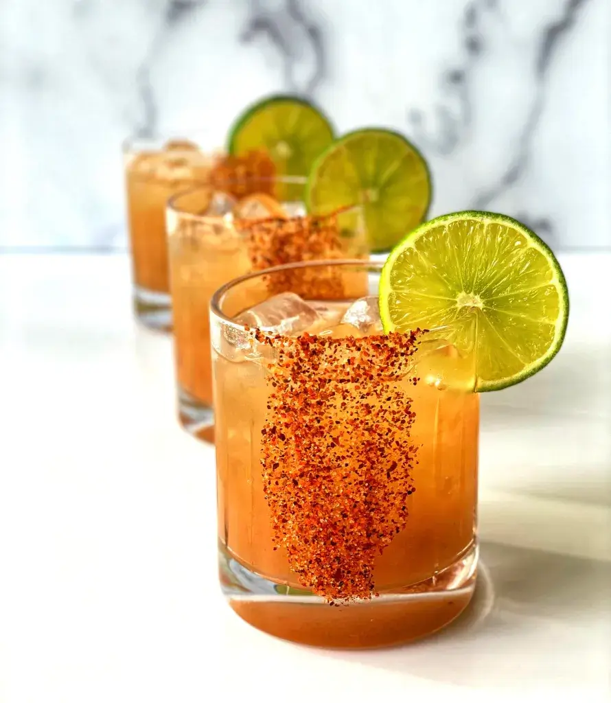 Three reddish cocktails garnished with lime.