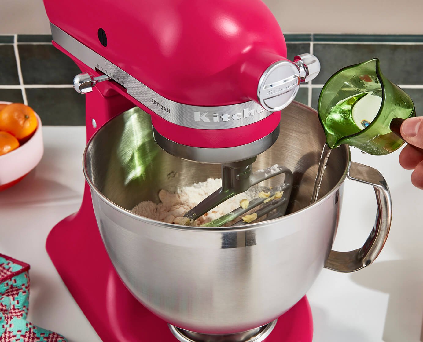 A closeup shot of a bright fuschia Kitchenaid stand mixer blending baking ingredients.