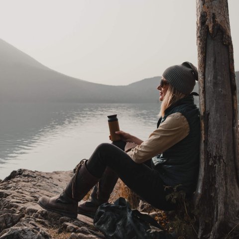 woman sitting against tree with mountain in background