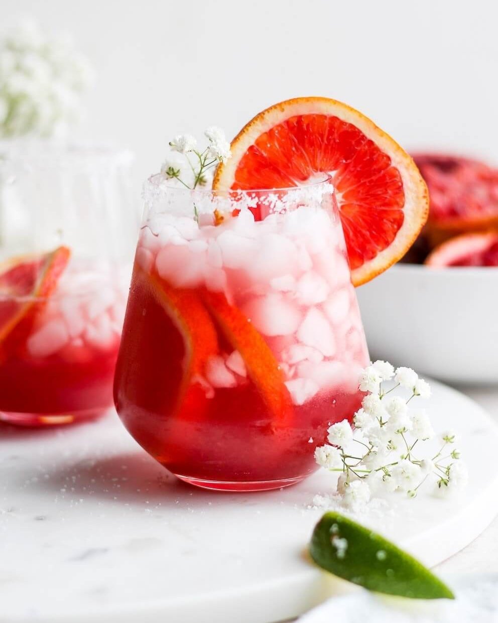 A glass with a red cocktail and blood orange wheel garnish.