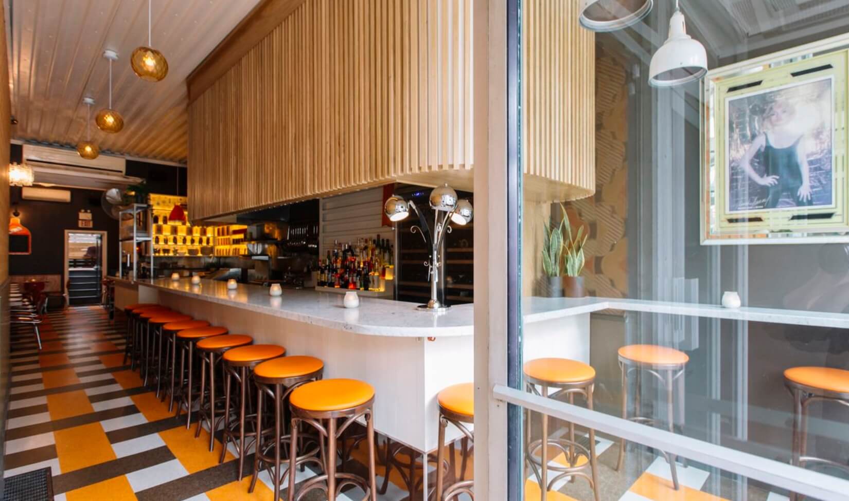 A dining room and bar in shades of orange shot from the doorway.