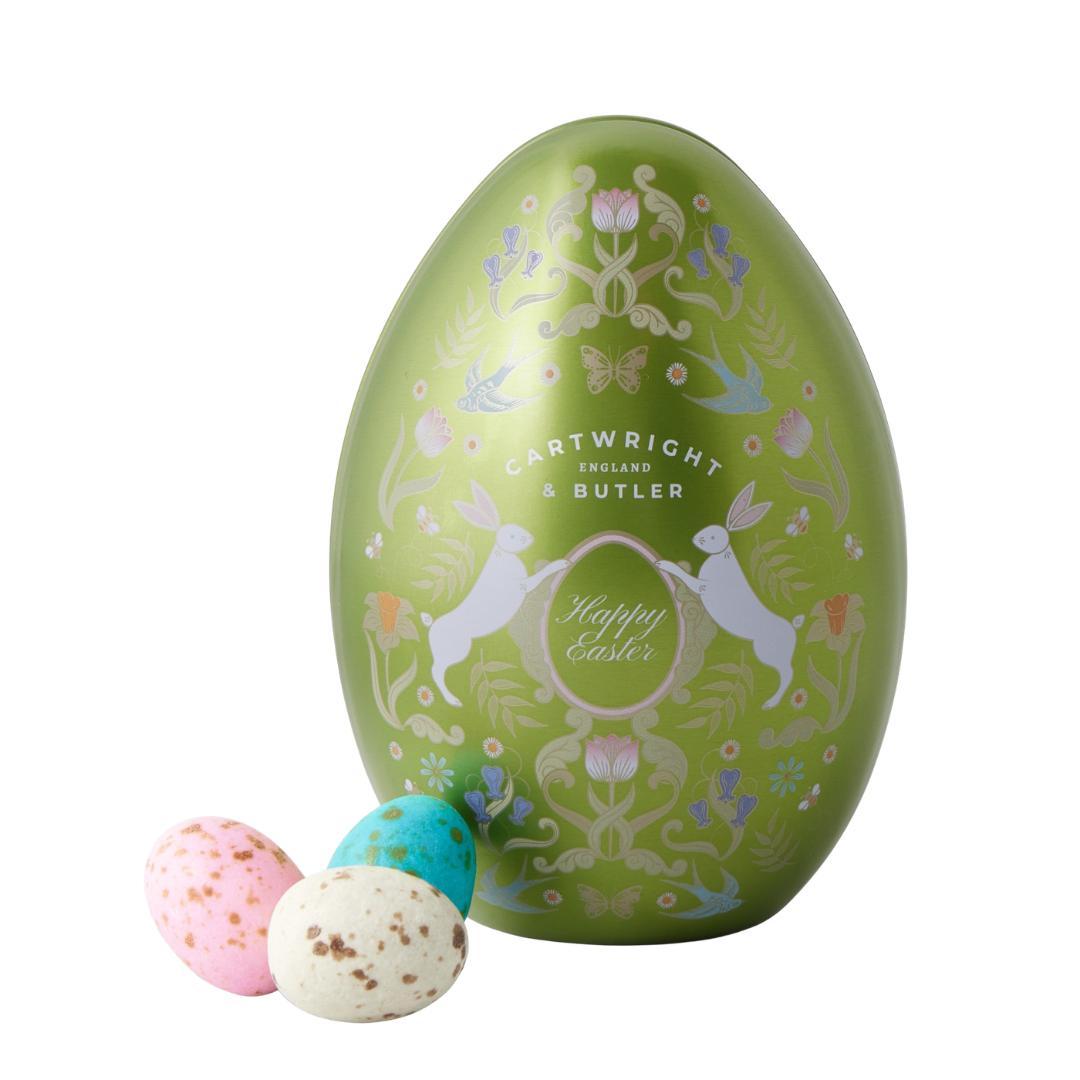 A large green egg-shaped tin and three robin's egg chocolates in front. 