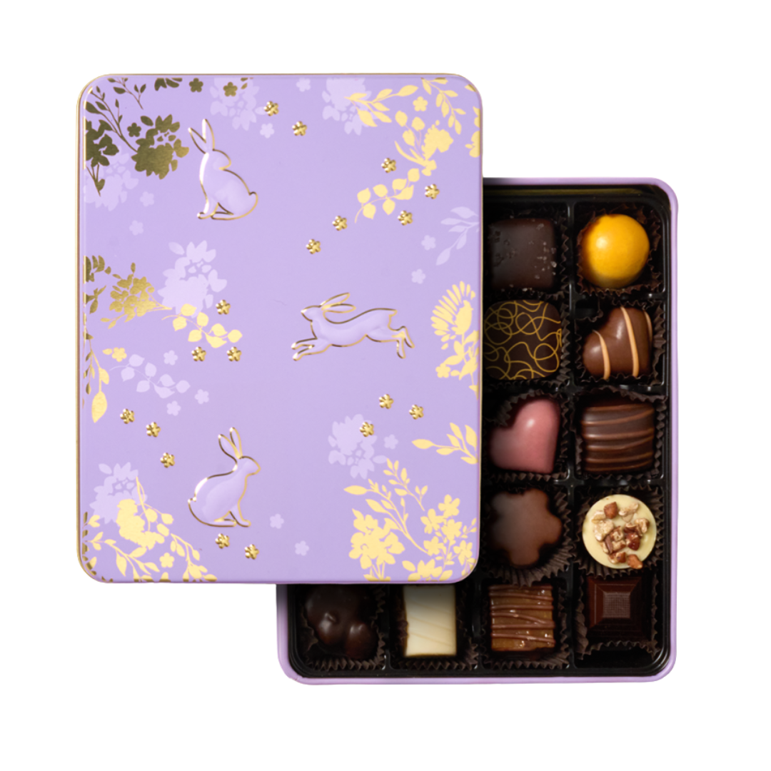 A rectangular purple metal tin opened to show chocolate truffles. 