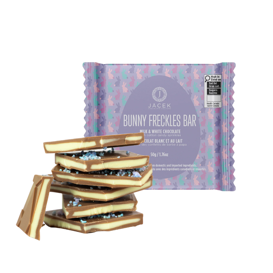 A stack of chocolate squares in front of a purple square package of chocolate.