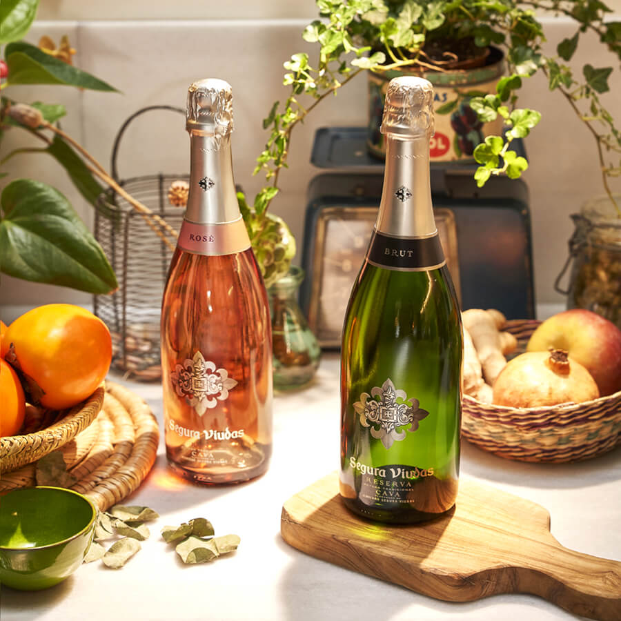 Two bottles of Segura Viduas on a countertop with greenery in the background.