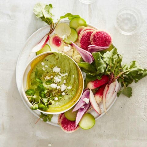 white plate with green vegetable dip and radishes