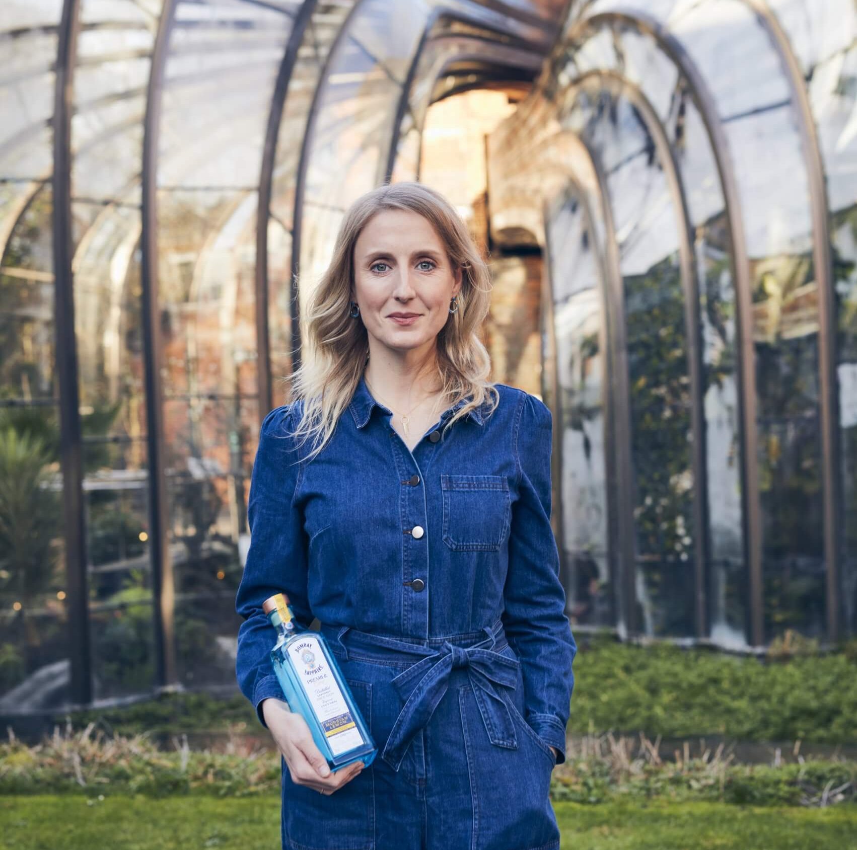 woman holding bottle in front of glass house