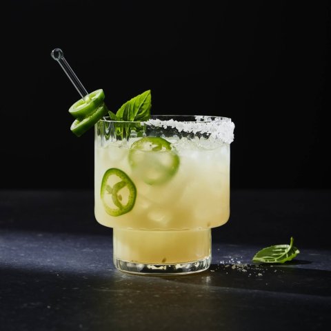 glass of lemon drink with jalapeno slices on black background