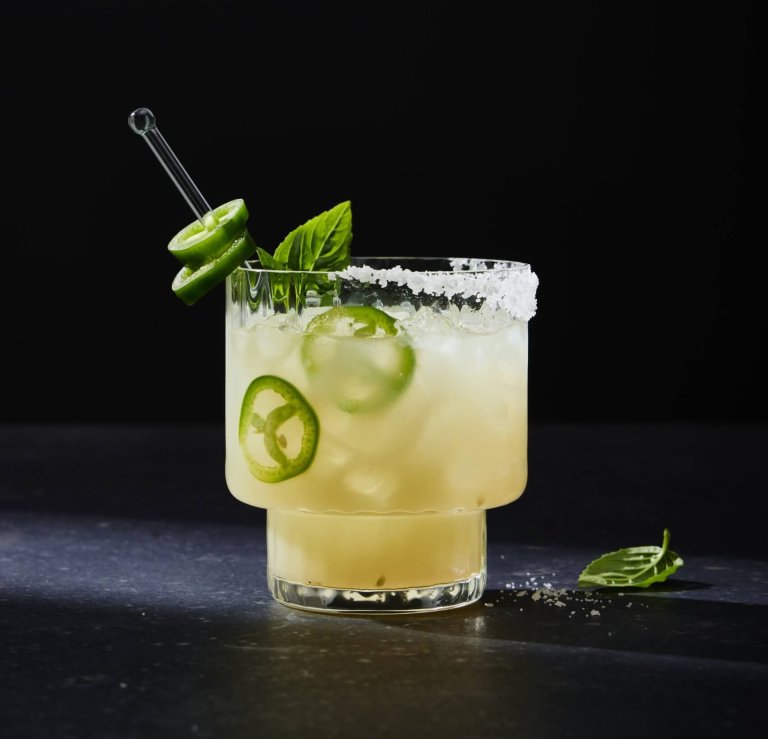 glass of lemon drink with jalapeno slices on black background