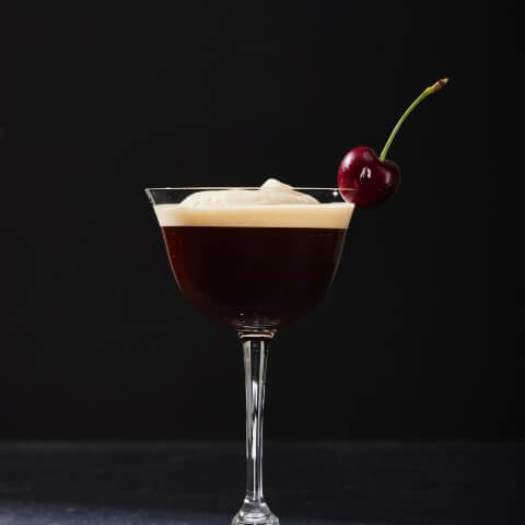 glass with coffee martini in it against black background