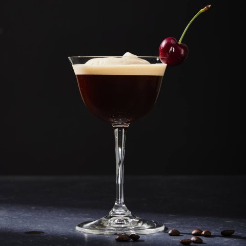 glass with coffee martini in it against black background