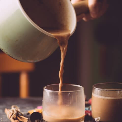 Pot pouring tea tea into glasses on a table