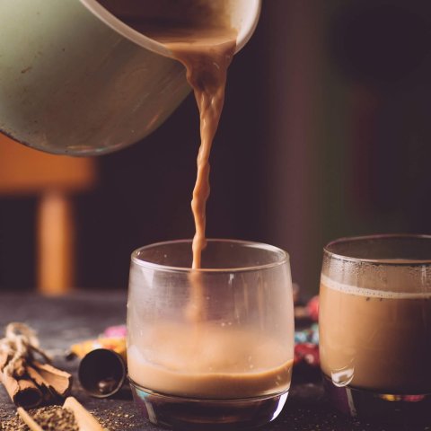 Pot pouring tea tea into glasses on a table