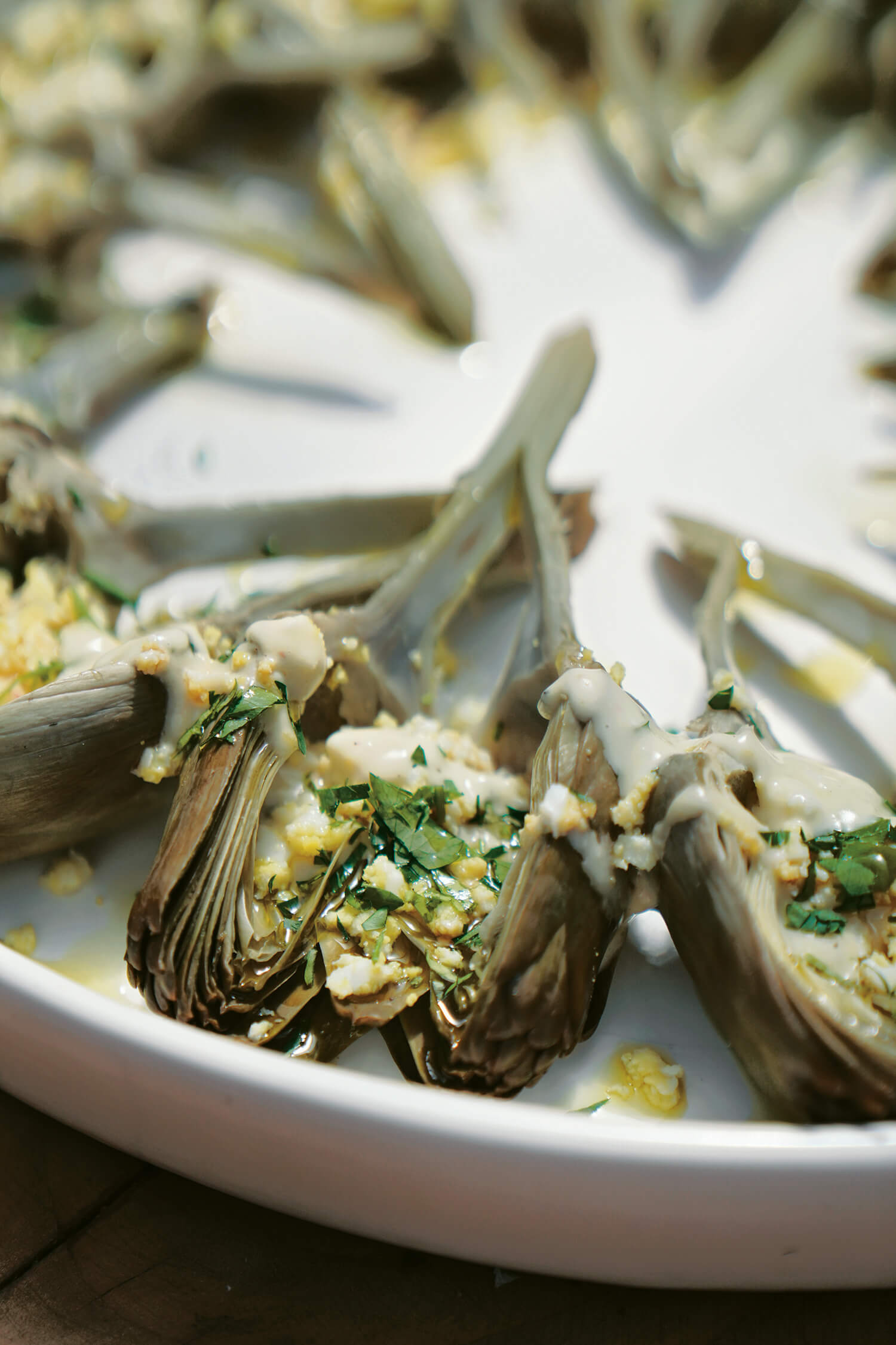 Artichokes sliced in half and arranged in a circle on a white plate