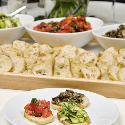 A white plate with three slices of bread that have various toppings, which are seen laid out in the background.