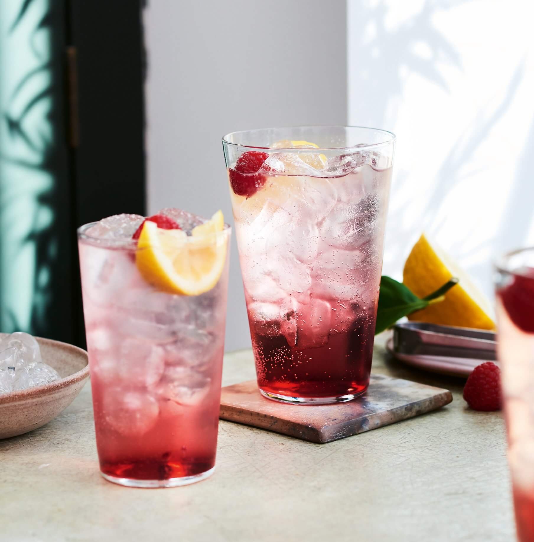Two water glasses with cocktails on a countertop