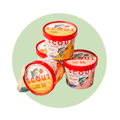 A stack of colourful containers and a small wooden spork on a light green circle graphic