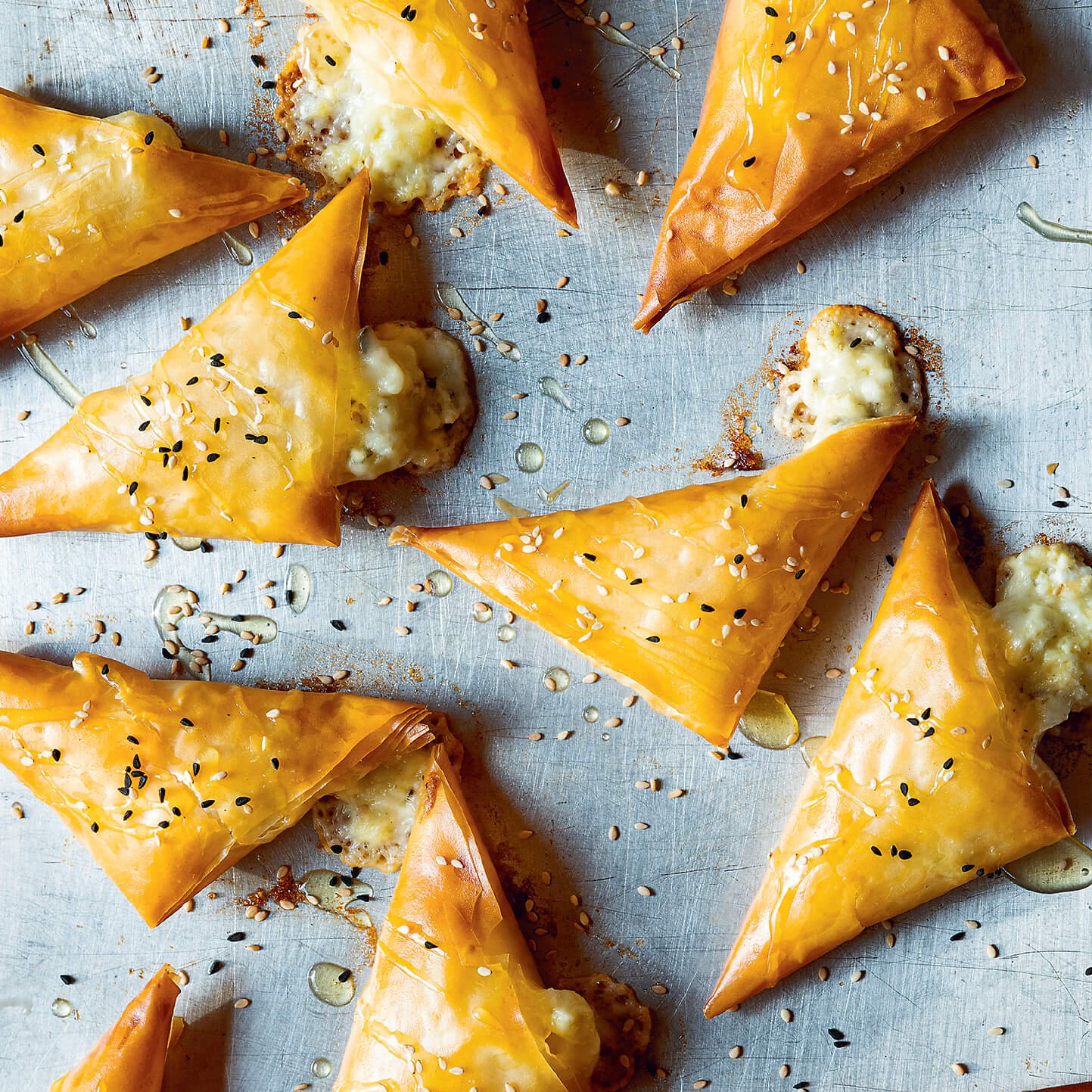 A closeup of phyllo triangles on a silver baking sheet