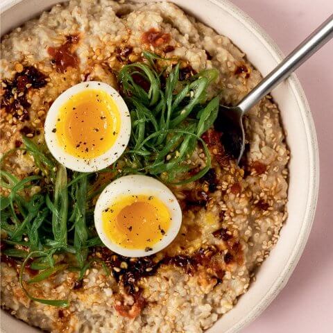 A bowl of oatmeal on a light pink background.