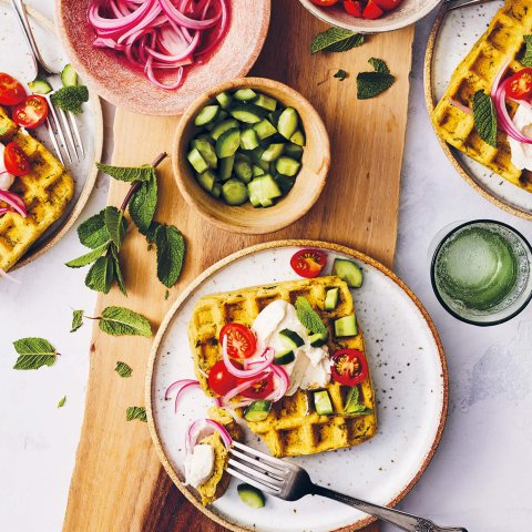 A table set with dishes that have waffles and various toppings.