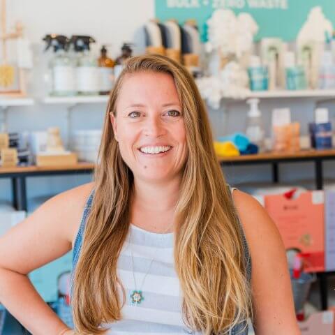 A woman smiling with store shelves in the background.