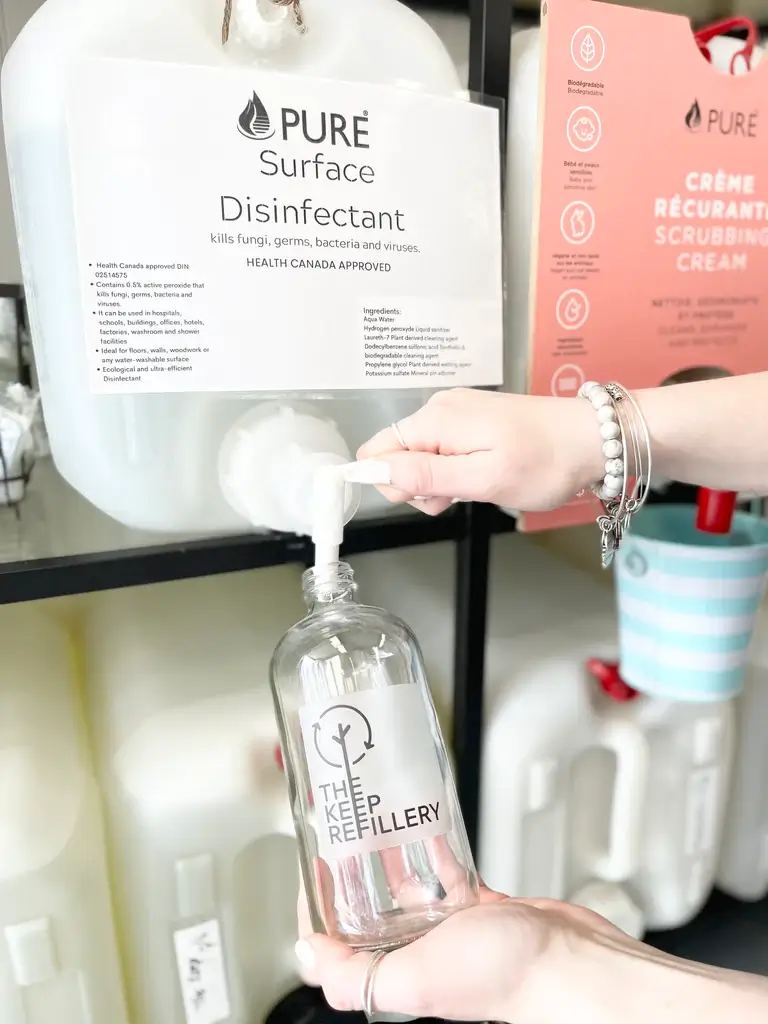 A person refilling a bottle from a large plastic container